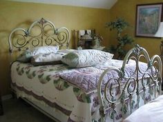 a bed sitting in a bedroom next to a lamp and pictures on the wall above it