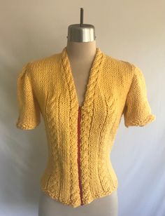 Adorable buttercup yellow 1940's reproduction soft chunky knit cabled cardigan! This was made from an original 1940's knitting pattern. Yarn is new, but red zipper is vintage. The yarn is ever so soft cotton, rayon, bamboo. It is cool to the touch. Cable pattern runs around the neck and down the front, under the bust and at the center of the sleeves.  Worn once, but it is clean and in excellent condition! Some very light pilling at the underarms. Made by yours truly! Measurements: would best fit Fitted Yellow Knit Sweater, Yellow Fitted Knit Sweater, Vintage Knitted Spring Cardigan, Fitted Vintage Knit Outerwear, Hand Knitted Fitted Tops For Fall, Fitted Hand Knitted Tops For Fall, Fitted Vintage Knitted Cardigan, Retro Fitted Knit Outerwear, Vintage Knitted Sweater For Spring