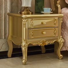 a gold nightstand with two drawers next to a bed