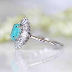 Victoria Neon Paraiba Tourmaline Ring ►Made of Sterling Silver, Rhodium Plated (S925) ►Accented with Simulated Diamonds (CZ) Center Stone: Paraiba Tourmaline Gemstone Creation: Lab-Created Stone Cut: Oval Color: Turquoise Gem size: 7.0 x 5.0 mm Carat Weight: 0.76 ct. Gemstone Origin: Brazil ►Handling time: 1-2 business days ►Free domestic USA shipping. Typically takes 2-5 business days. ►Wrapped & ready to give in a beautiful box. Turquoise Emerald-cut Gemstone Ring, Turquoise Emerald Cut Gemstone Ring, Turquoise Gemstone Rings With Emerald Cut, Emerald Cut Turquoise Gemstone Ring, Elegant Turquoise Diamond Ring, Turquoise Emerald Ring For Anniversary, Fine Jewelry Turquoise Ring With Halo Setting, Turquoise Ring With Halo Setting In Fine Jewelry Style, Turquoise Halo Setting Fine Jewelry Ring