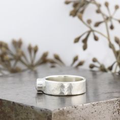 "This wide, modern Artifact ring has a hammered surface that looks like a modern relic. This diamond alternative engagement or right hand ring is made with a white sapphire and is made to order in your size in about four weeks. The Artifact Ring is like a relic from an ancient civilization, a prize from an archaeological dig. The surface of this sterling silver ring has layers of subtle texture that add depth and dimension to the ring. With a polished finish and a gorgeous bezel set stone as the Modern Sterling Silver Hammered Rings, Modern Wide Band Concave Ring For Anniversary, Silver Hammered Signet Ring For Anniversary, Modern Wide Band Engraved Ring For Anniversary, Modern Concave Wide Band Ring For Anniversary, Modern Engraved Wide Band Ring For Anniversary, Modern Sterling Silver Signet Ring With Bezel Setting, Modern Polished Moonstone Ring For Anniversary, Modern Moonstone Ring With Polished Finish For Anniversary