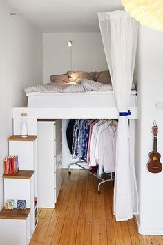 there is a bunk bed in the room with clothes on it and a guitar hanging from the ceiling