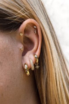 a close up of a woman's ear with three different types of earrings on it