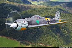 a fighter jet flying over a lush green forest