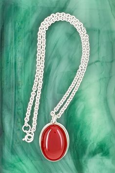 This carnelian pendant is bezel set on a cable chain. And this smooth, polished gemstone in burnished red makes a nice statement in a strapless style, office attire, t-shirt or sweater.

Size: The pendant length is 1", width is 11/16", gemstone is 25 x 18 millimeters, chain length 14”, chain width is 2.8 millimeters Oval Red Carnelian Jewelry, Red Carnelian Jewelry With Cabochon, Luxury Red Carnelian Jewelry With Cabochon, Red Polished Pendant Necklaces, Red Carnelian Oval Necklace, Red Oval Pendant Necklace With Spiritual Style, Red Pendant Necklace With Polished Finish, Red Oval Pendant Spiritual Necklace, Red Oval Carnelian Necklace