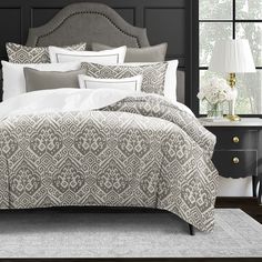 a bed with white and grey comforters in a bedroom