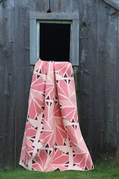 a pink and white blanket sitting in front of a barn