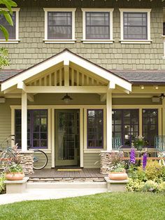 a house with two bikes parked in front of it and landscaping around the porch area