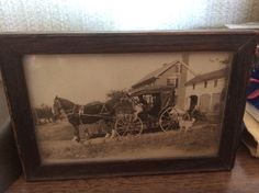 an old photo of a horse and buggy in front of a house on a table