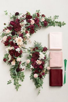 an arrangement of flowers and greenery laid out on a white surface