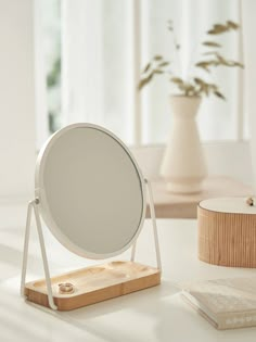 a mirror sitting on top of a wooden stand next to a vase with flowers in it