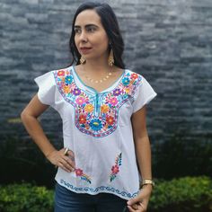 This handmade Mexican shirt has been embroidered with beautiful colorful flowers. It will look great with any color skirt or pants. It has short sleeves and a scoop neckline. This is a nice comfortable casual cotton shirt. It is perfect as a gift for a friend or someone special. About Our Items: Each one of our items is handmade/hand woven by Indigenous communities of Chiapas and Oaxaca in Mexico. Great care has been taken to ensure the quality and uniqueness of each item we sell. Our items are White Embroidered Beach Shirt, White Floral Embroidered Beach Shirt, White Floral Embroidered Shirt For Beach, White Floral Embroidered Shirt For The Beach, Casual Floral Embroidered Top For Festivals, Summer Embroidered Shirt With Multicolor Embroidery, Bohemian Embroidered Summer Shirt, Summer Bohemian Embroidered Shirt, Casual Short Sleeve Blouse With Intricate Embroidery