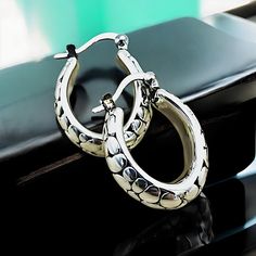 Elevate your jewelry collection with our exquisite Lightweight Oval Cobblestone Design Hoop Earrings, meticulously crafted from premium 925 Sterling Silver. Each earring boasts a delicate hollow construction, ensuring both comfort and elegance. The dimensions of these sophisticated hoops are approximately 18.5 mm in width and 21.4 mm in length, offering a striking presence without overwhelming. They are subtly stamped with '925' to certify their sterling silver composition. Experience the perfec Luxury Teardrop Hoop Earrings In Sterling Silver, Luxury Silver Metal Hoop Earrings, Tarnish Resistant Sterling Silver Oval Earrings, Luxury Silver Tarnish-resistant Huggie Earrings, Luxury Silver Pierced Hoop Earrings, Elegant Tarnish Resistant Silver Hoop Earrings, Elegant Silver Tarnish-resistant Hoop Earrings, Silver Round Huggie Earrings Gift, Silver Oval Huggie Earrings For Gift