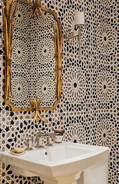 a white sink sitting under a mirror next to a wall mounted faucet in a bathroom