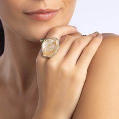 This natural and authentic ring features a free-shaped Baroque pearl, accented by a small Green Sapphire dot on the side. Set in 925 Silver plated with White Rhodium and 18K Gold, this piece is a unique blend of contemporary design and wabi-sabi philosophy, celebrating the beauty of the transient and imperfect. Crafted as a singular piece, it is meant for someone who appreciates the natural elegance of imperfection. Metal: 925 Silver Stones: Baroque Pearl, Sapphire Plating: White Rhodium, 18K Gold  PLEASE NOTE: This ring features a natural Baroque Pearl, which may exhibit color variations, small cracks, and an imperfect surface. These characteristics are not flaws but rather signs of authenticity. Luxury Natural Stones Ring Jewelry, Luxury Natural Stone Ring Jewelry, Luxury Jewelry Ring With Natural Stones, Elegant Yellow Gold Ring With Natural Stones, Elegant Yellow Gold Rings With Natural Stones, Elegant Formal Rings With Natural Stones, Elegant Jewelry With Natural Stones In Open Ring Shape, Elegant Open Ring With Natural Stones Jewelry, Elegant Open Ring With Natural Stones