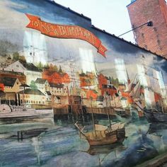 a mural on the side of a building with boats and buildings painted on it's sides