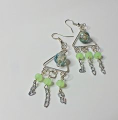 two pairs of earrings with green beads hanging from the earwires on a white surface