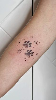 a person with a tattoo on their arm that has a dog's paw and stars