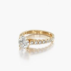 a yellow gold engagement ring with diamonds on the band and an oval cut diamond in the center