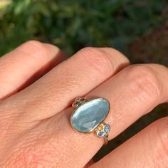 A baby blue Aquamarine is Set in 14k yellow gold with a pair of deep blue and teal sapphires and vibrant blue zircons. Emily's handmade seagrass band finishes this stunning piece. Approx stone size: 15 mm x 9mm Approx stone weight: 4.1cts Mohs Hardness: 7.5-8 This one of a kind piece is handmade to order in Emily's Hudson Valley studio. If you have questions about sizing, shipping or need help deciding please reach out to us! Turquoise Sapphire Ring With Accent Stones, Fine Jewelry Turquoise Sapphire Ring With Accent Stones, Gold Aquamarine Gemstone Ring, Oval Multi-stone Aquamarine Ring, Oval Aquamarine Multi-stone Rings, Yellow Gold Aquamarine Gemstone Jewelry, Fine Jewelry Light Blue Sapphire Ring With Accent Stones, Fine Jewelry With Aquamarine And Rose Cut Diamonds, Fine Jewelry Aquamarine With Rose Cut Diamonds