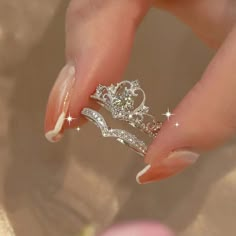 a woman's hand holding two rings with diamonds on them and the middle one has a diamond in it