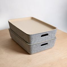 two storage boxes sitting on top of a wooden table