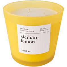 a yellow candle that is sitting on a white surface with a label reading sicilian lemon