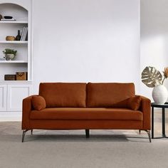 a living room with an orange couch and two vases on the table next to it