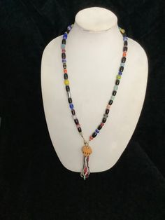 This necklace is made from multicolored beads and it has a tassel at the front. The tassel has a gold ball and the multicolored fronds hanging from it. It measures 30 inches and the tassel measures 5 inches. Hand-strung Multicolor Beaded Lariat Necklace, Adjustable Long Tassel Necklace With Dangling Beads, Adjustable Multicolor Beaded Tassel Necklace, Bohemian Multicolor Tassel Necklace With Colorful Beads, Adjustable Multicolor Tassel Necklace With Colorful Beads, Multicolor Tassel Necklace With Round Beads, Multicolor Beaded Tassel Necklace For Festivals, Adjustable Multicolor Tassel Necklace With 108 Beads, Multicolor Hand-strung Lariat Necklace