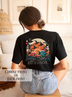 This stunning t-shirt showcases a striking and stylized illustration of a flock of migratory birds in flight, capturing their sense of freedom and adventure.  Did you know that migratory birds have the ability to navigate using a range of cues, including the position of the sun, the Earth's magnetic field, and even the stars? It's an incredible feat of navigation, and one that continues to amaze scientists and bird enthusiasts alike. This t-shirt is the perfect choice for anyone who loves nature Graphic Tee With Graphic Design As Gift, Graphic Tee With Graphic Design For Gift, Graphic Tee Tops As Gift, Black Printed Tops For Fan Merchandise, Graphic Tee Printed T-shirt As Gift, Graphic Tee Printed T-shirt For Gift, Artistic Graphic Print Top As A Gift, Graphic Print Tee Shirt As Gift, Artistic Graphic Print Tops As Gift