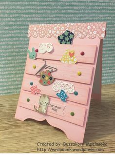 a pink card with lots of buttons on the front and bottom, sitting on top of a wooden table