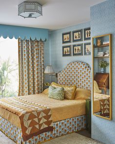 a bed room with a neatly made bed next to a window and a mirror on the wall