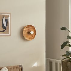 a room with a chair, potted plant and pictures on the wall above it