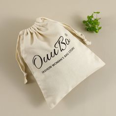 a drawstring bag sitting on top of a table next to a small plant