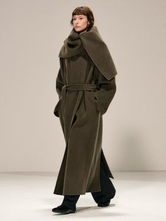 This luxurious double-breasted coat crafted from 100% wool features a versatile shawl collar that can be styled as a dramatic cape, complete with a detachable belt for a customized silhouette. The maxi-length design offers superior warmth and sophistication, while thoughtful details like side slit pockets, hidden snap closures, and a full twill lining elevate its collectible appeal. Available in both khaki and black, this handmade piece combines timeless elegance with practical functionality, ma Shawl Collar Coat, Collar Coat, Collared Coat, Double Breasted Coat, Shawl Collar, Wool Coat, Hijab Fashion, Fashion Illustration, Double Breasted