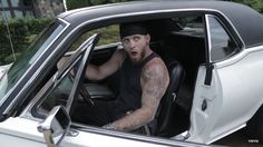 a man sitting in the driver's seat of a car with his tongue out