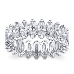 a white gold ring with oval cut diamonds on the sides and rows of leaves around it