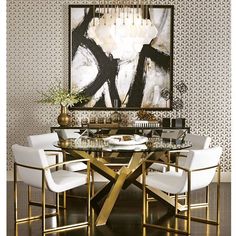 a dining room table with white chairs and a painting on the wall in the background