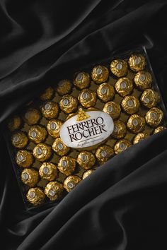 a box filled with gold foiled chocolates sitting on top of a black cloth