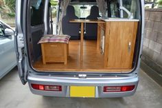 the back end of a van with an open door and wooden furniture in it's cargo area