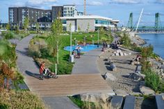 people are walking and sitting on benches near the water