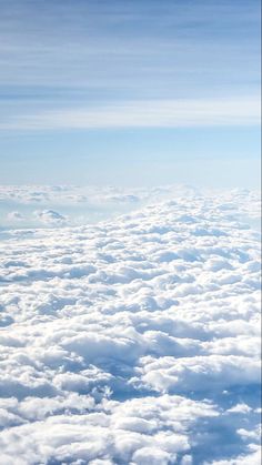 the view from an airplane looking down on clouds and blue sky with white fluffy clouds