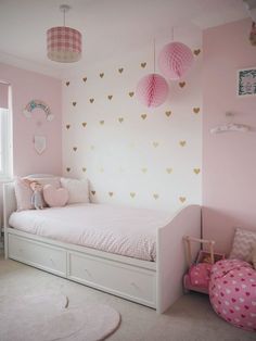 a child's bedroom with pink walls and hearts on the wall, including a bed