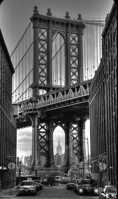 black and white photograph of the manhattan bridge in new york city, ny with cars driving under it