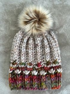 a multicolored knitted hat with a pom - pom on top