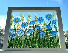 a glass window with blue flowers and green grass