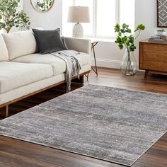 a living room with a couch, chair and rug on the hardwood floor next to a window