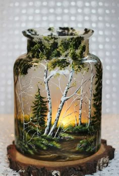 a glass jar with trees painted on it