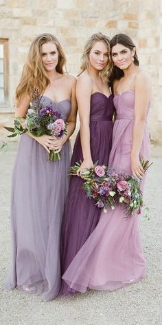 three bridesmaids in strapless purple gowns with flowers and greenery on their bouquets