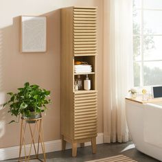 a white bath tub sitting next to a tall wooden cabinet in a room with pink walls